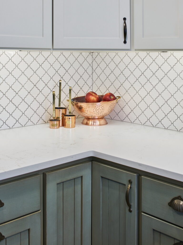White lantern-shaped tile with gray grout meeting the quartz counter at an inside corner.