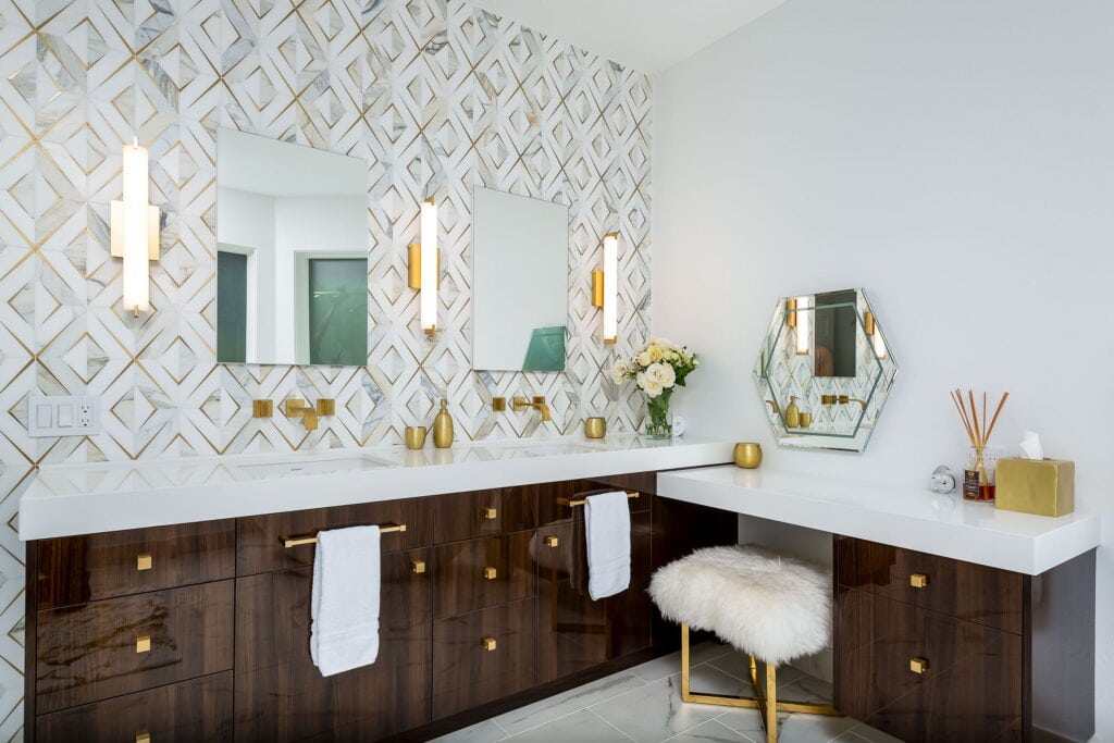 Remodeled West Eugene spa bathroom with a marble-and-brass inlay tile wall, high-gloss walnut double vanity, and a corner makeup table.