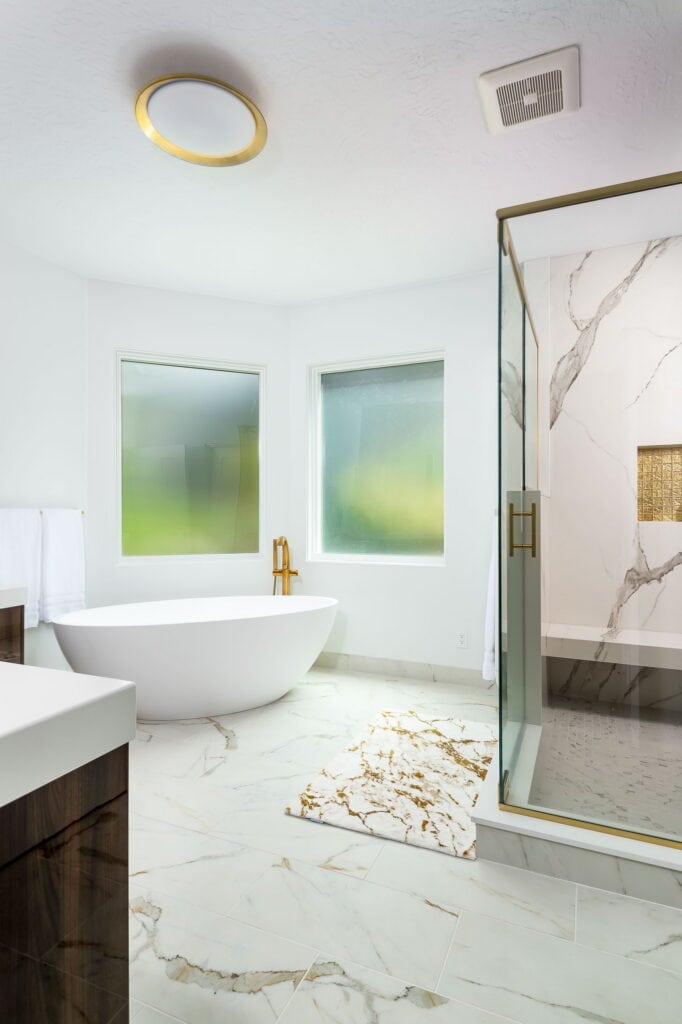 The tub and shower share the marble floor, with a towel warmer set between them.