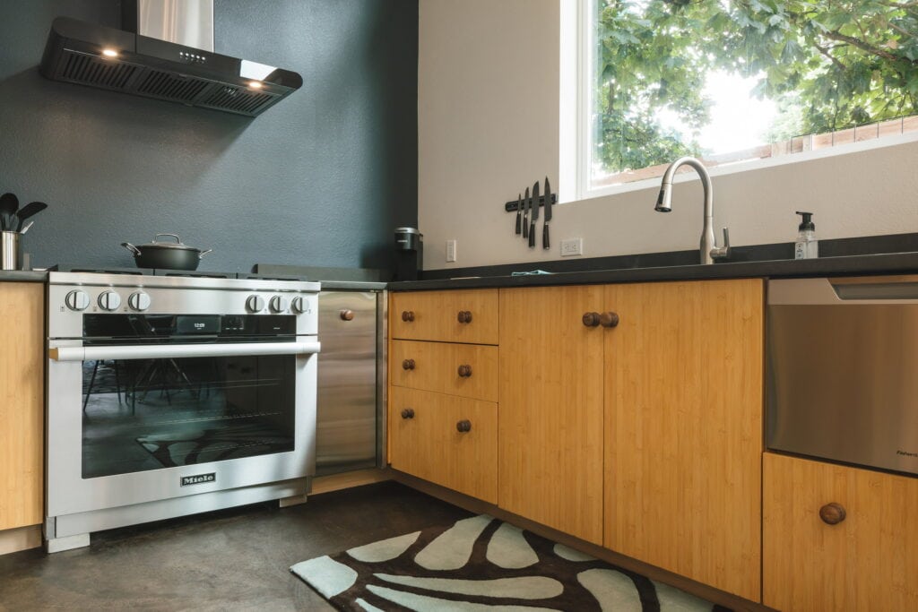 Bamboo cabinet fronts and dark quartz counters along the sink run.