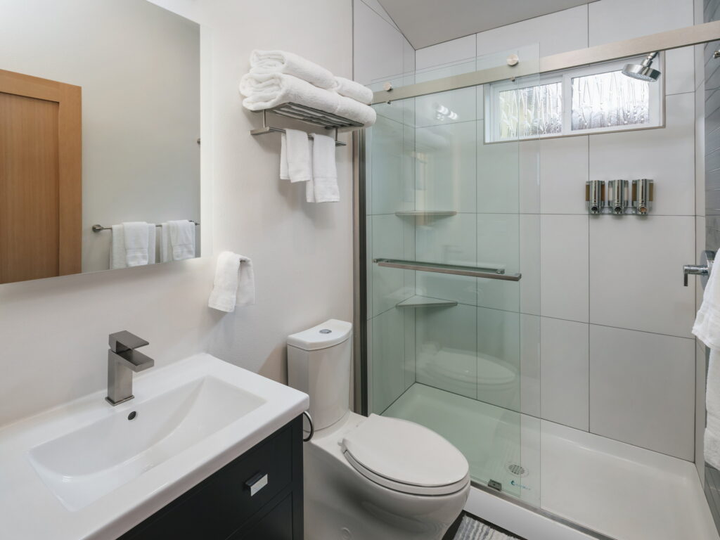 Full bathroom with a large-format tile shower, sliding glass door, and a dark vanity.