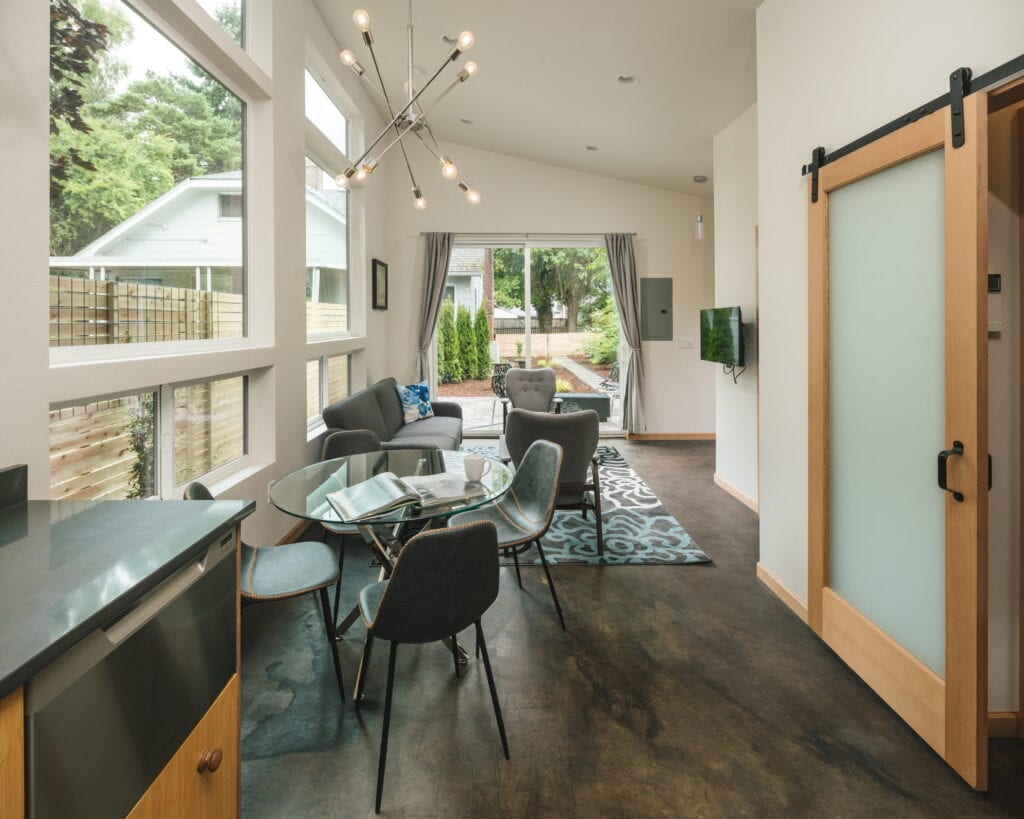 Dining and living area looking toward the patio slider, with a frosted-glass barn door to the bedroom at right.