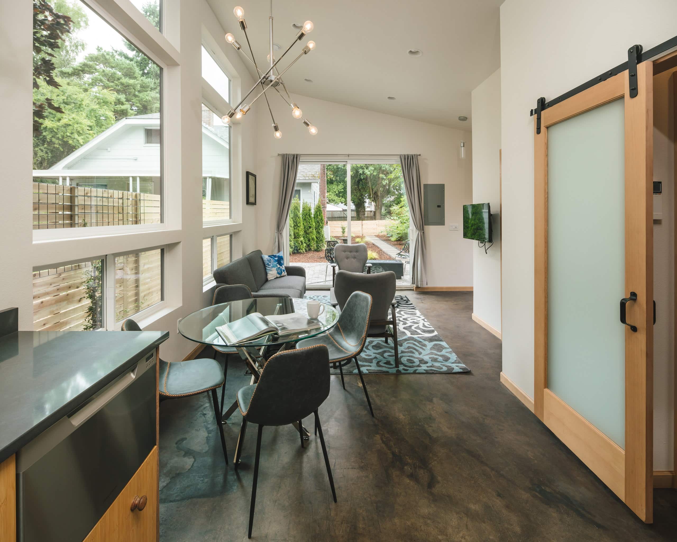 Dining and living area looking toward the patio slider, with a frosted-glass barn door to the bedroom at right.