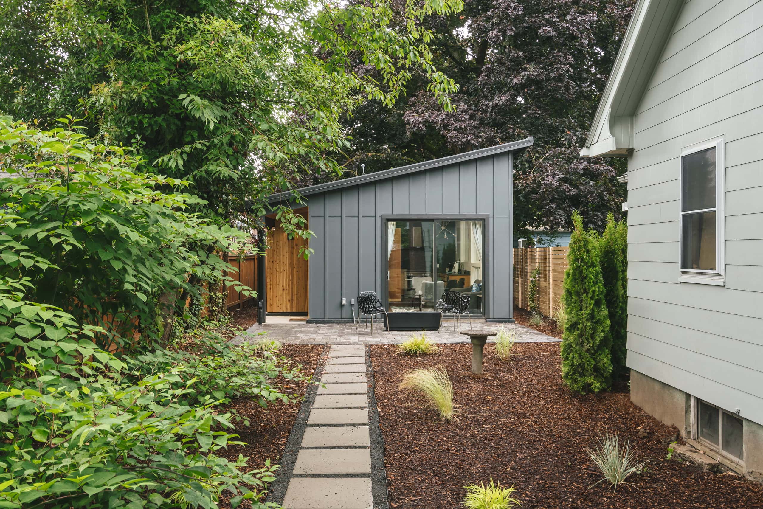 The ADU from the garden, with a stepping-stone path leading to the patio and sliding glass door.