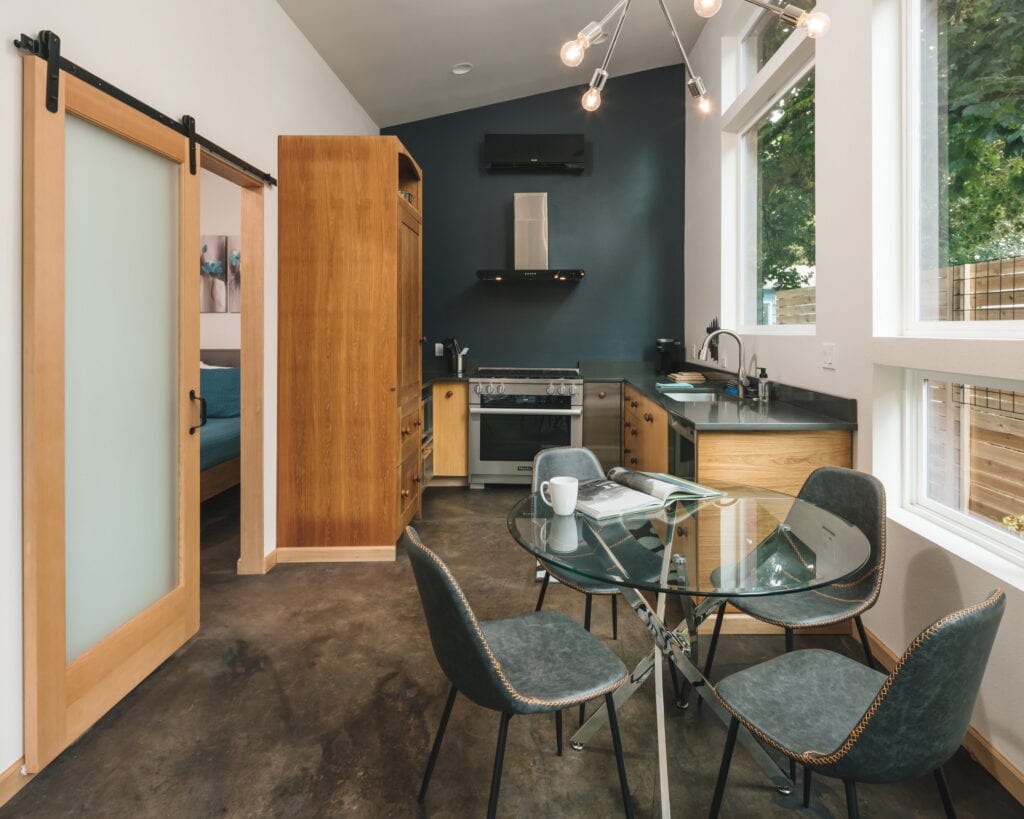 Kitchen and dining from the living end, with a frosted-glass barn door opening to the bedroom.