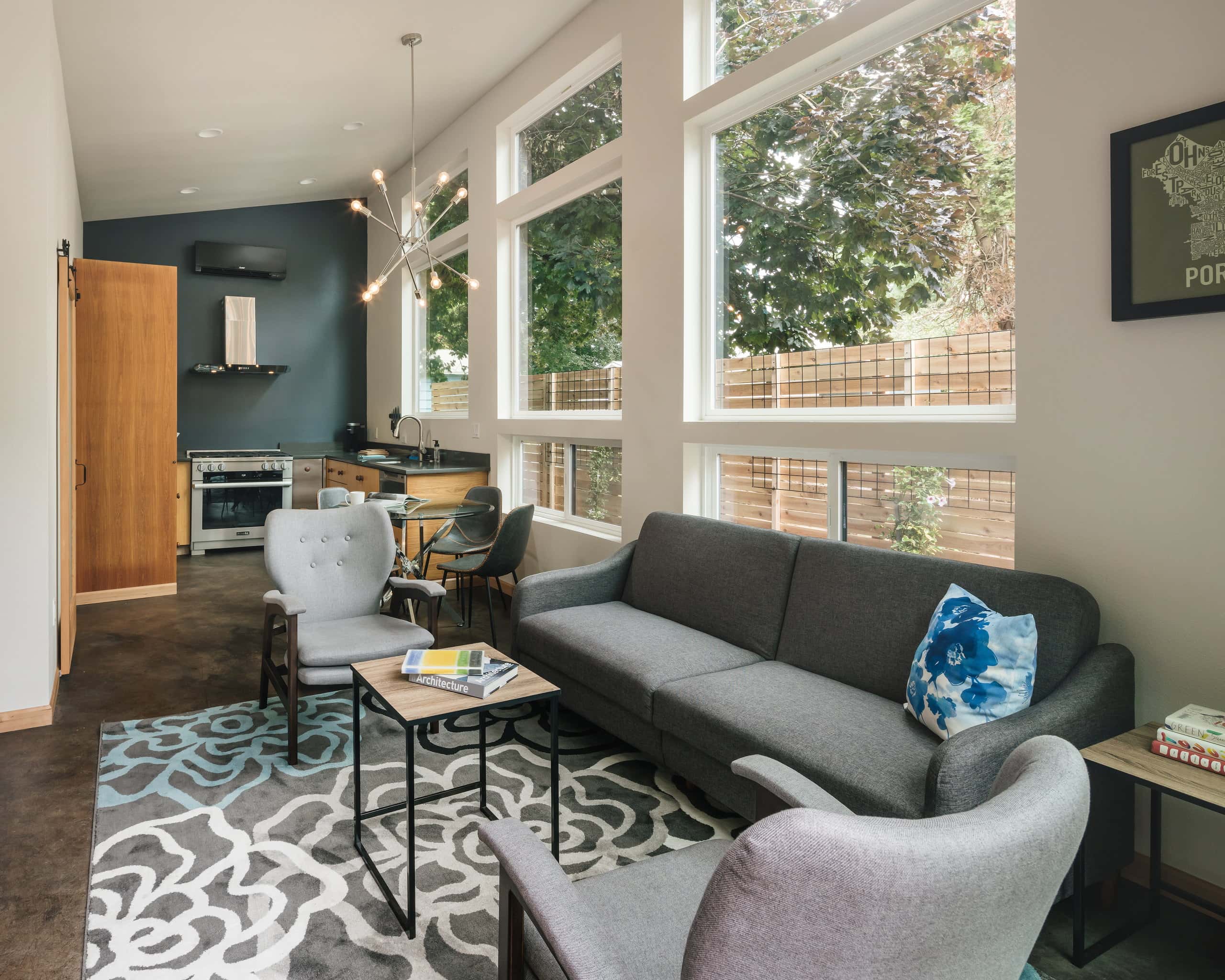 Open living area of the ADU, with a wall of clerestory windows, stained concrete floors, and the kitchen beyond.