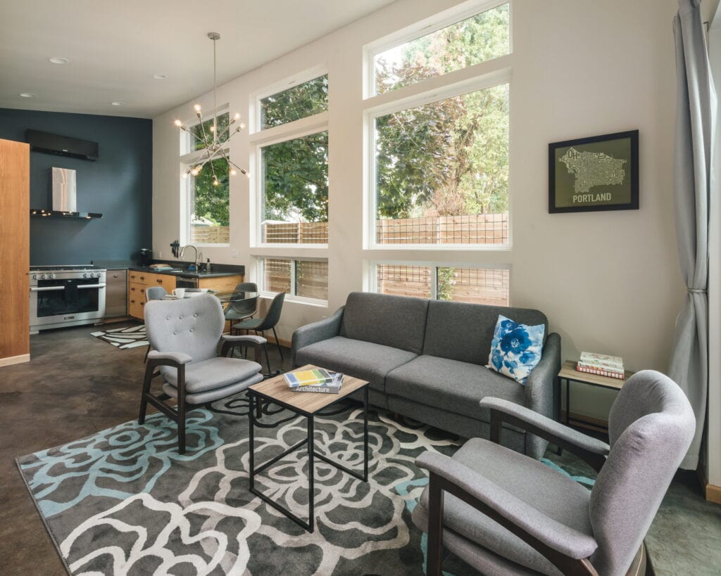 The living area, with the kitchen along the far wall and clerestory windows above the fence line.