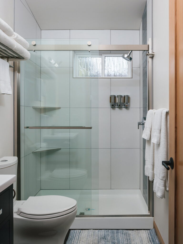 Tiled shower with sliding glass door and privacy window.