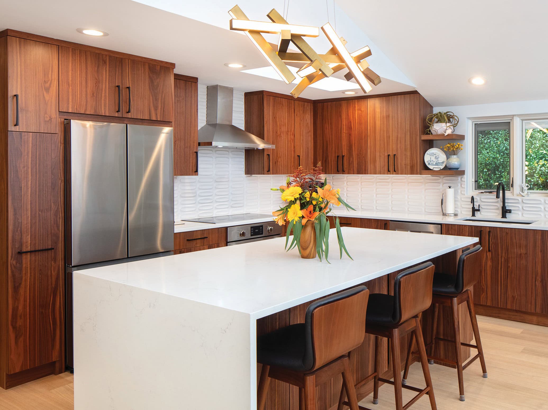 A remodeled kitchen with walnut cabinets and an island with three stools