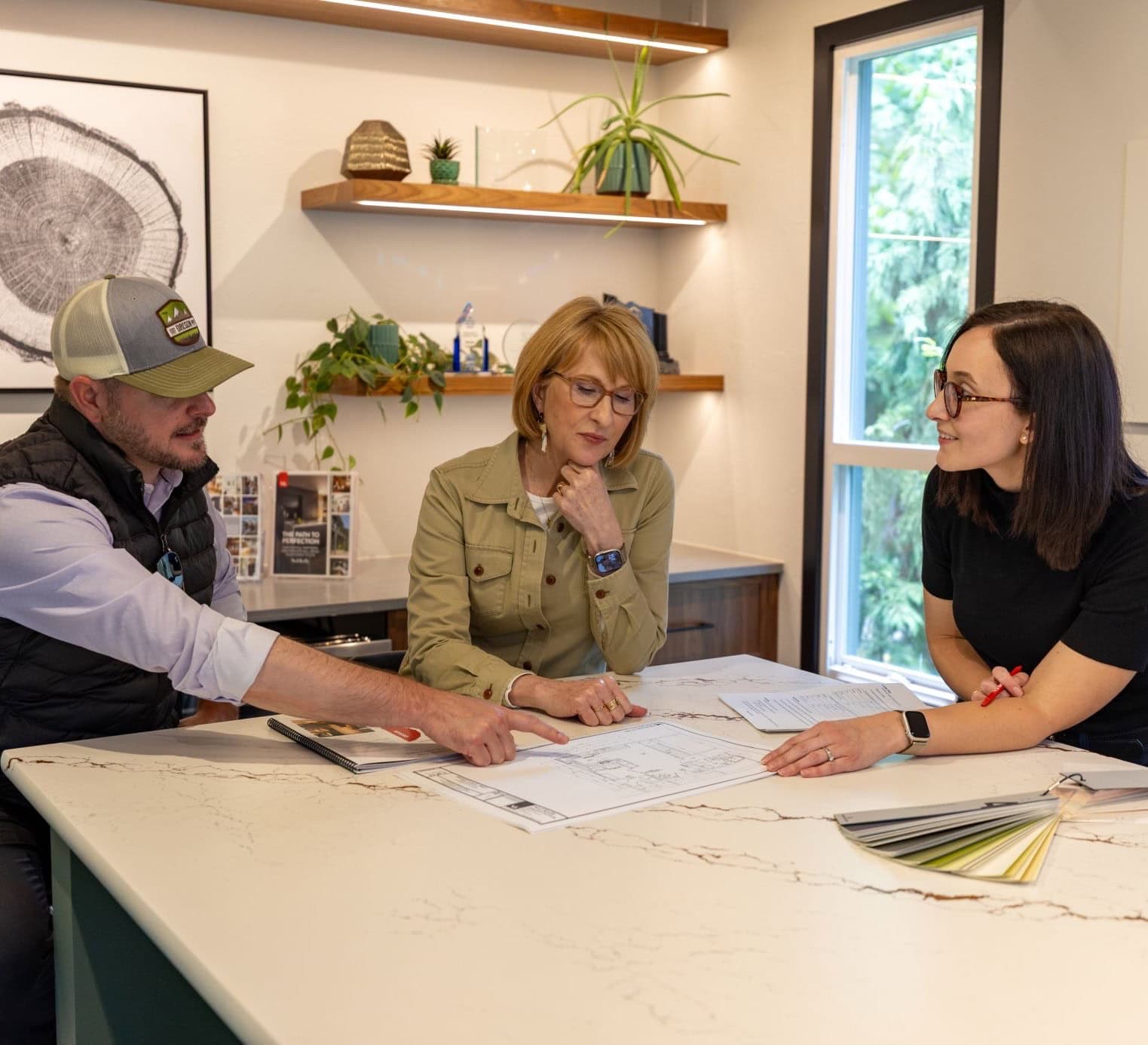 Neil Kelly designers and project manager collaborating on a remodeling project with plans on the table in front of them.