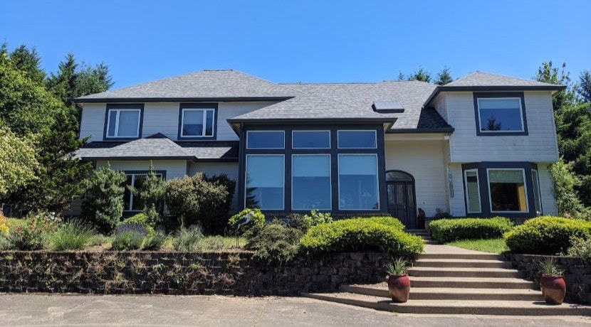 A home exterior with new windows, white paint, black trim, and stairs leading to the front door