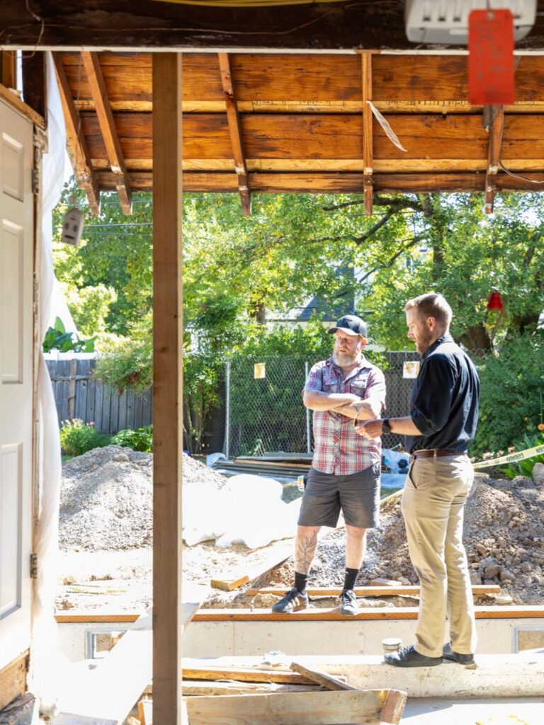 Neil Kelly project managers stand on a job site with visible foundation work