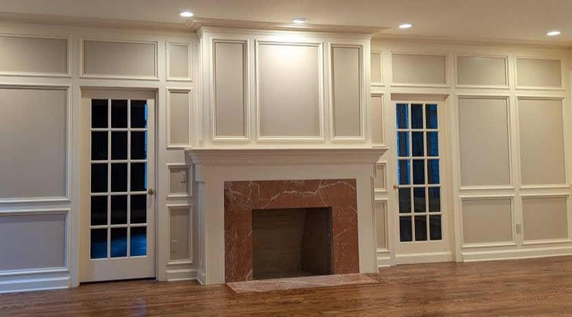 A fireplace and mantel with lots of detailed millwork on the surrounding wall