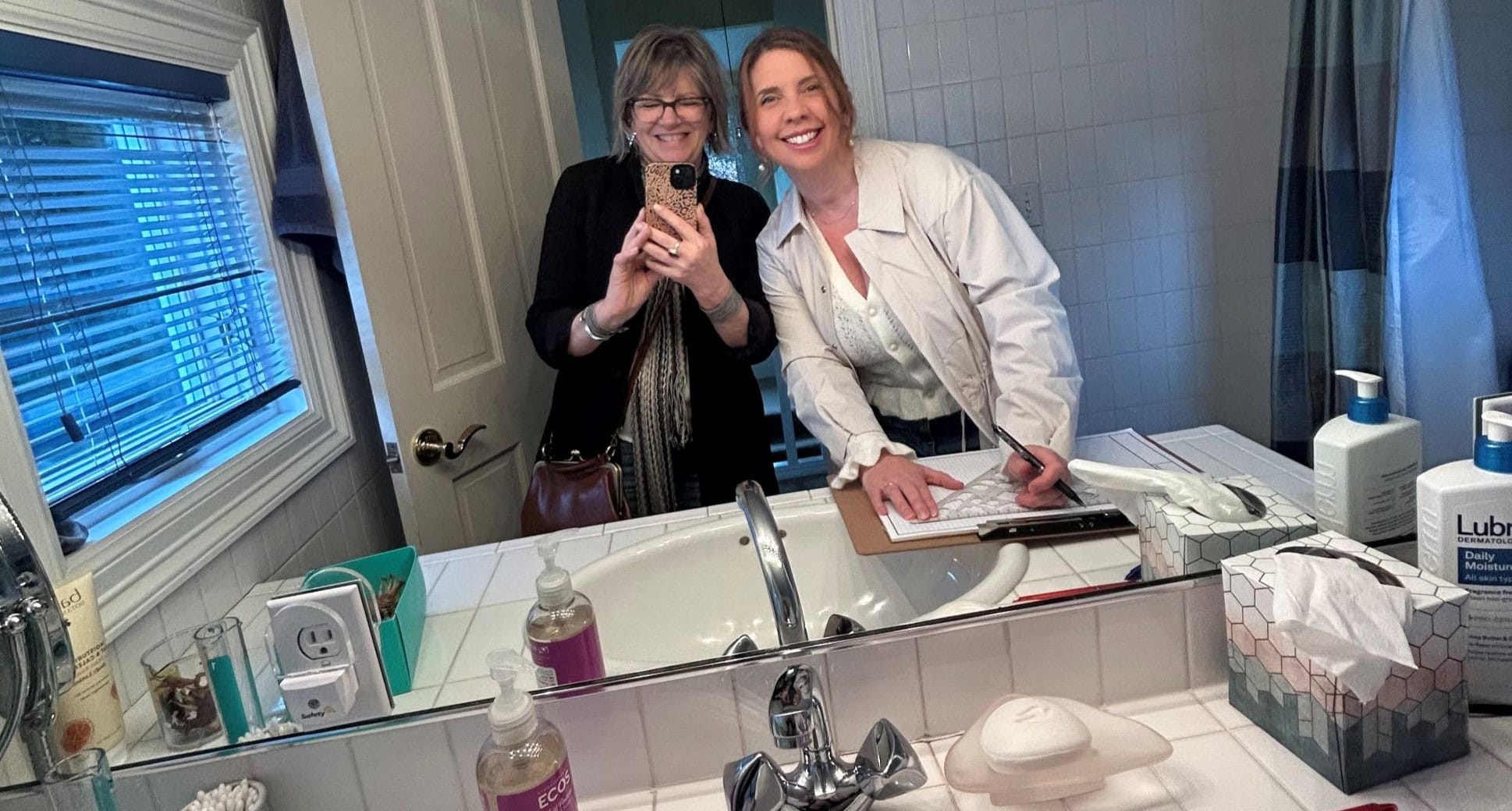 A Neil Kelly designer and design assistant take notes of an existing bathroom during an in-home remodeling consultation