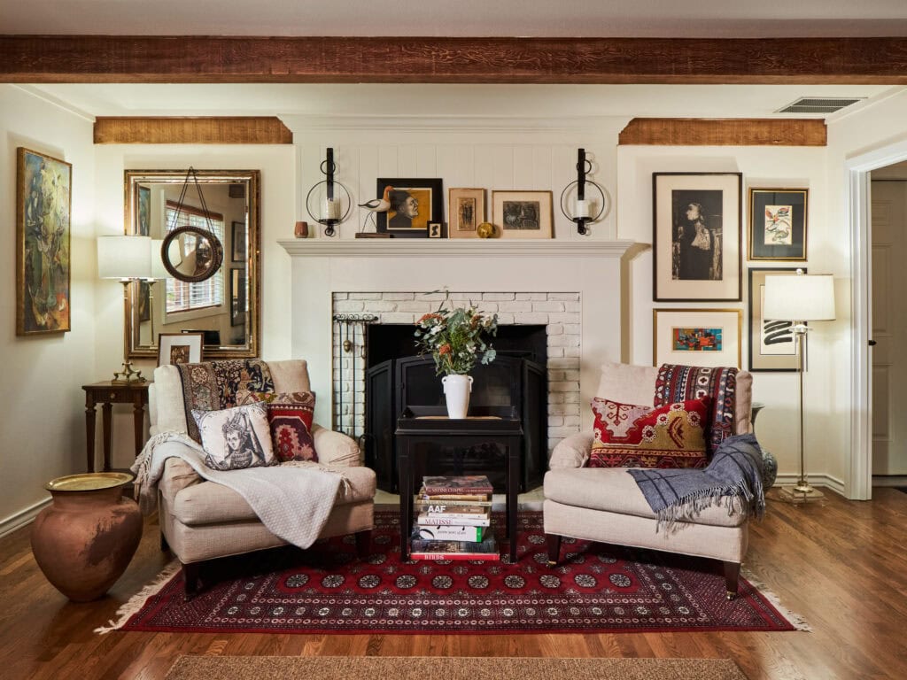 A transitional, old-world-inspired living room with a fireplace, mantel, and two cozy chairs