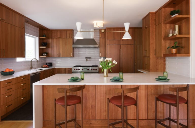 A remodeled kitchen with cherry wood cabinets, a white tile backsplash, and high-end appliances