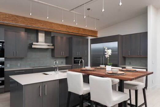 Bend Tetherow Custom Home 005 Modern custom home kitchen with reclaimed beams, walnut butcher block, sintered stone countertop, and track pendant lighting.
