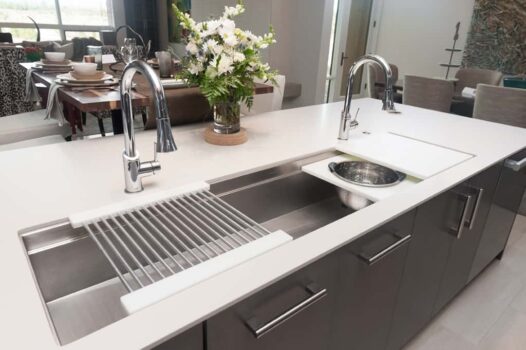 Close up of kitchen island with large undermount sink with two faucets