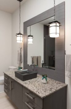 Bend Tetherow Custom Home 020 Modern custom home bathroom with recycled glass countertop, tiled mirror, vessel sink, and pendant lights.
