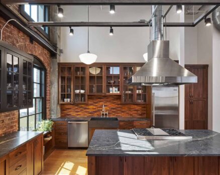 Industrial condo kitchen with brown cabinets and black countertops