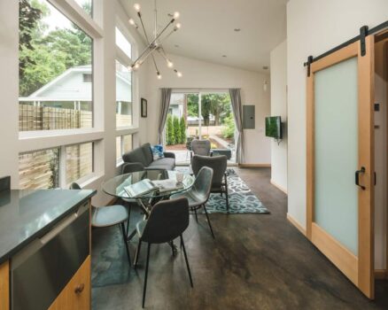 SE Portland Accessory Dwelling Unit ADU 07 Modern open concept accessory dwelling unit with large windows, concrete floors, sliding glass door, and chandelier.