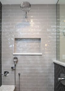 Alt text: Tiled shower with built in storage and rain water faucet renovation
