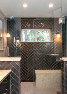 Alt text: Glass and black herringbone tile walk-in shower and recessed lighting
