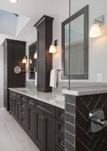 Alt text: Side view of master bathroom with black herringbone tile and two sinks