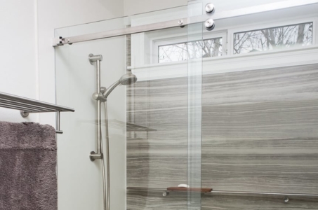 Chrome adjustable shower head in a glass walk-in shower with matte grey walls.