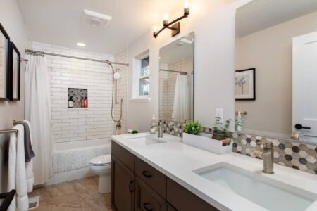 The guest bath features dual vanity and elegant tilework.
