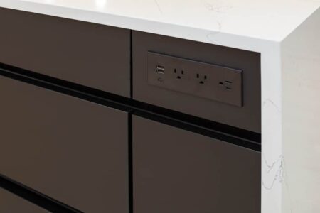 The kitchen island features power outlets for electrical appliances or devices.