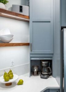 Kitchen appliance garage with a coffee maker inside and a light blue wooden door.