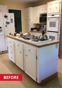 Cooking island in the middle of a kitchen with white cabinetry and a gas range.