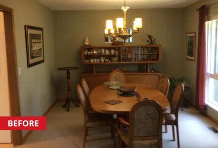 Dark dining space with a hanging light over a wooden table with six seats.