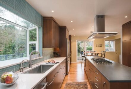 Modern kitchen with an under-mount stainless steel sink and a center island with a gas stove and ceiling fan.
