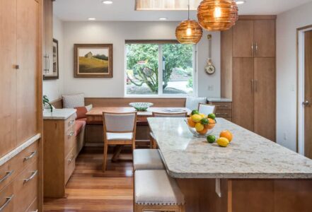 Kitchen island with a quartz overhang countertop and two cushioned stools.