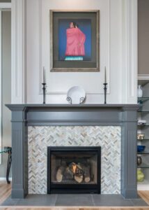 Modern kitchen with a quartzite island with a gas range, stainless steel air vent, and four black bar chairs.