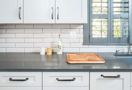 Wooden cutting board on top of quartz countertops with flat eased edge detail.