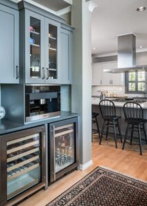 Built-in Miele Coffee System on a counter above two wine and beverage fridges, and glassware cabinets above.