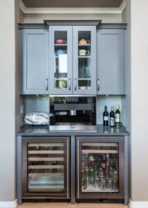 Built-in Miele Coffee System on a counter above two wine and beverage fridges, and glassware cabinets above.