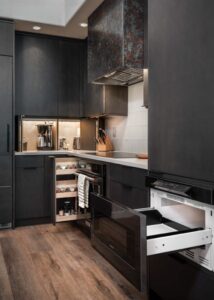 An open drawer microwave built into dark-stained kitchen cabinets.