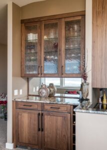Bar with walnut cabinets outside of a kitchen with 42-inch tall granite countertops that spill into the kitchen countertop.