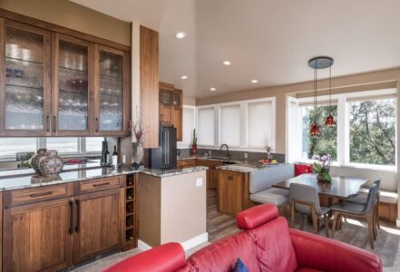 Bar with walnut cabinets outside of a kitchen with 42-inch tall granite countertops that spill into the kitchen countertop.