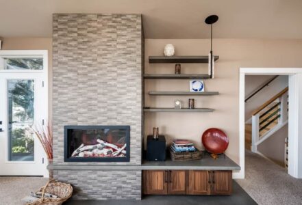 Staggered floating concrete shelving the the right of a stone fireplace hearth.