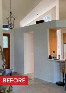 A white wall that has a doorframe for the entrance to a kitchen space.