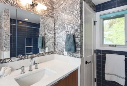 Bathroom with a wall light fixture above a long rectangular mirror and bathroom sink area.