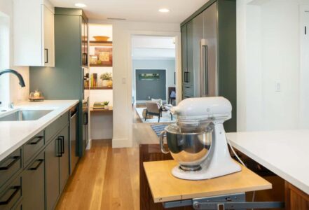 White stand mixer resting on a pull out appliance shelve in a kitchen.