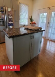 Kitchen island with a granite countertop and grey cabinets below.
