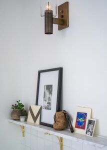 Floating shelf with a small framed image, a small potted plant, and a few small paintings.
