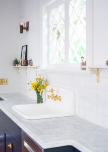 White sink with brass handles built into light marble countertops from Meta Marble & Granite.
